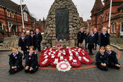 Children lay their hand-made wreath on war memorial